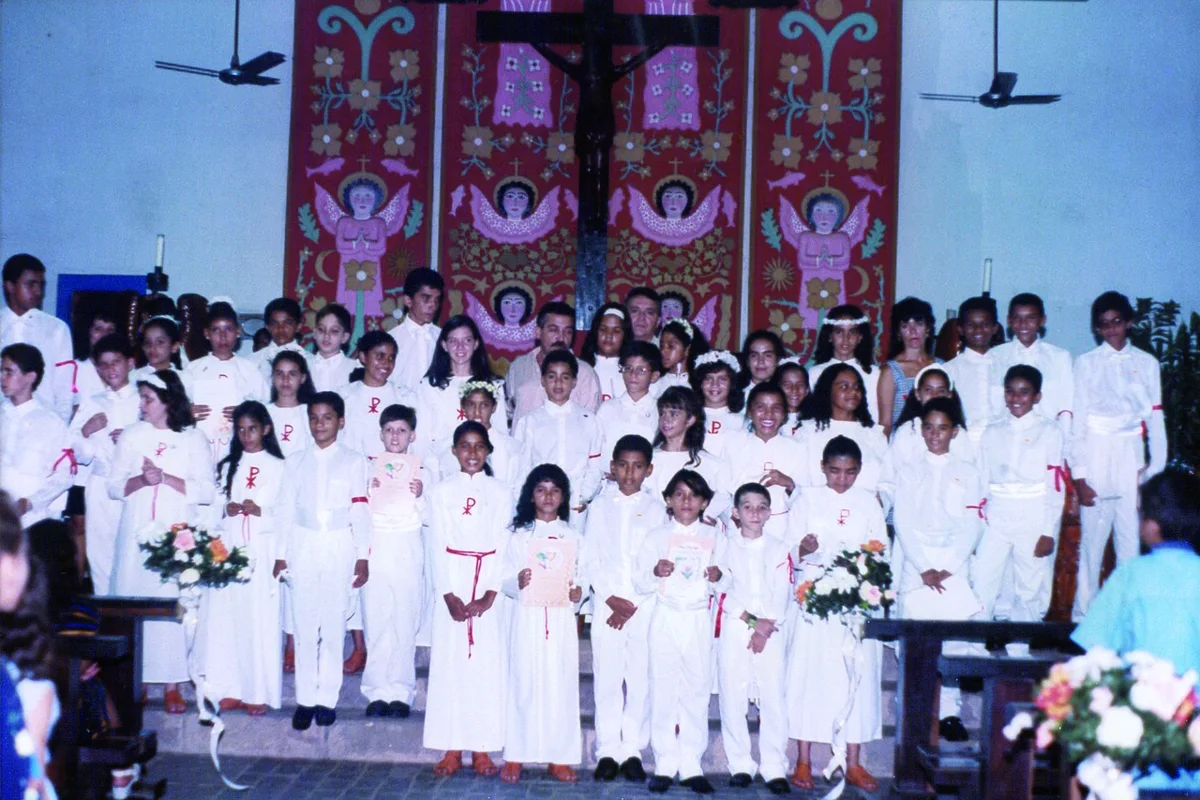 Crianças de branco na Primeira Comunhão diante do altar